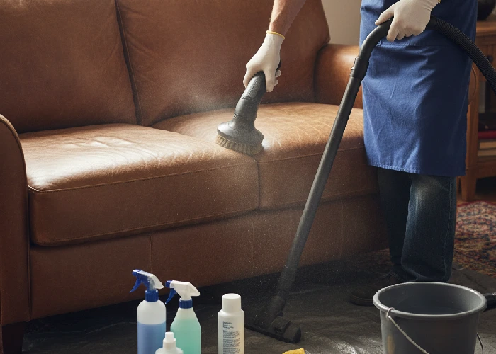 Leather couch cleaner removing dust and stains from a faded leather sofa using professional cleaning tools.